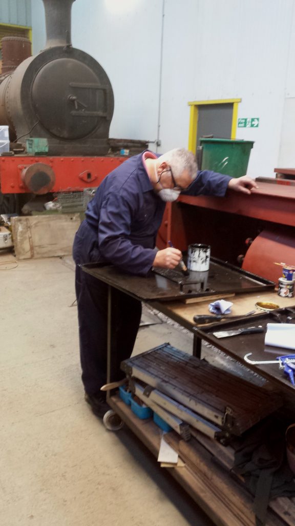 John Davis paints the gas holder door after the new warning sign has been attached