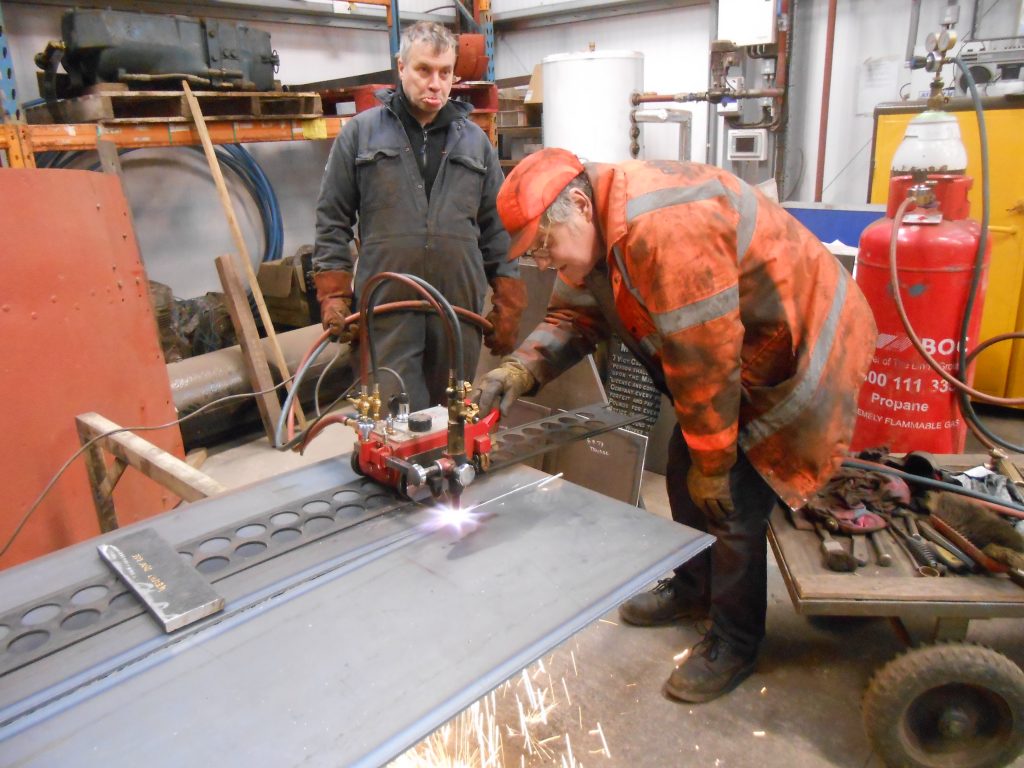 George pulls a funny face as Keith cuts metal for Wootton Hall's tender