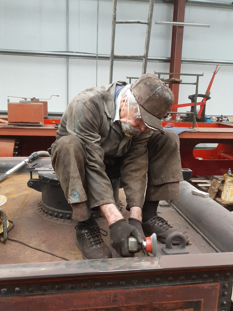 Fred applying a cup wire brush to the well on the back of FR 20's tender