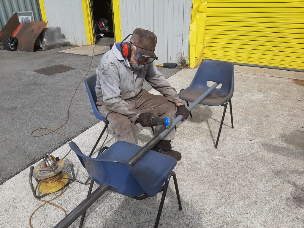 Fred removing paint from one of FR20's hand rails