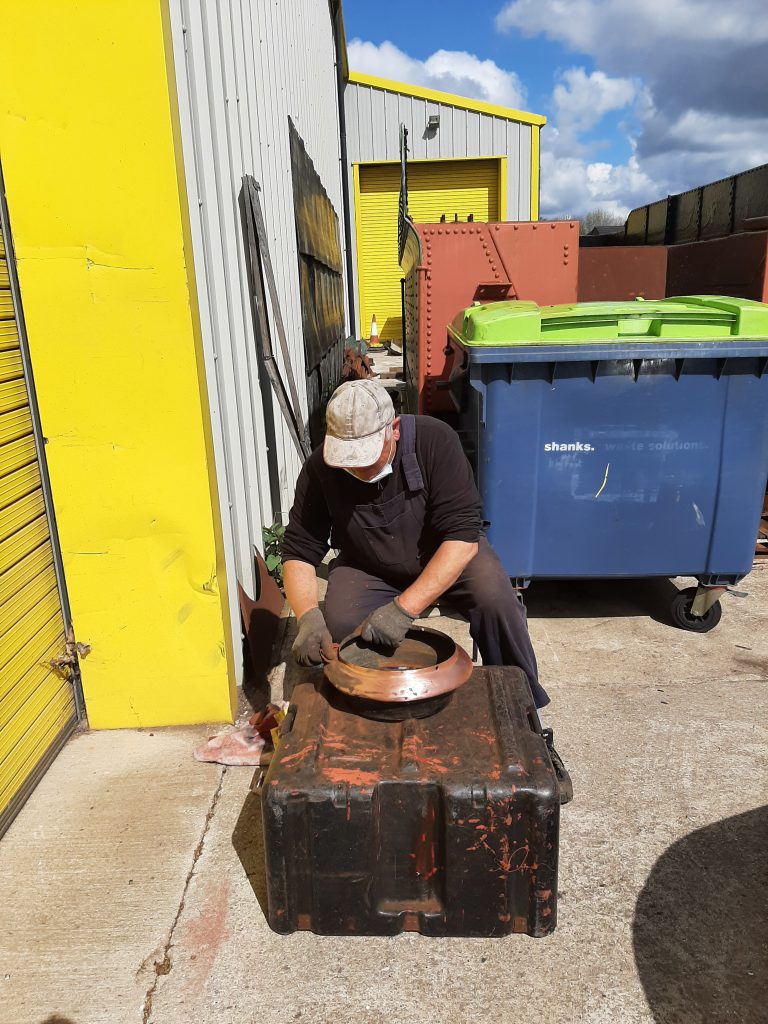 John Davis polishes the copper top on Fluff's chimney