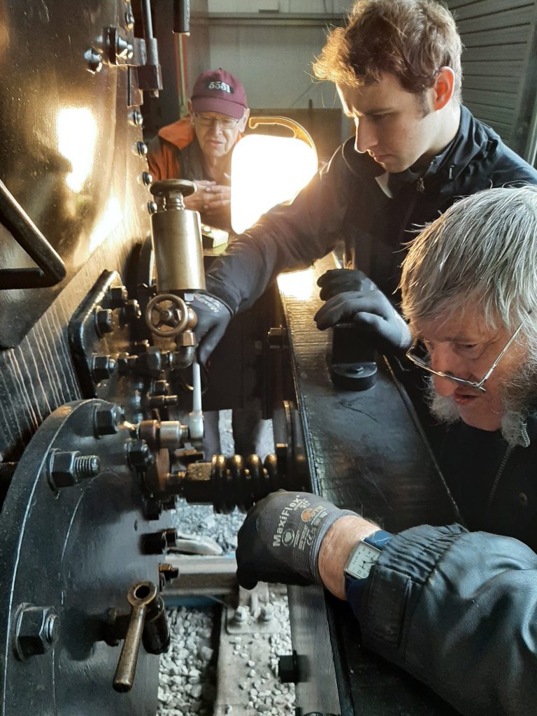 Sam and Alan fit joints to the valve spindle tail rod covers on FR 20, watched by John Dixon