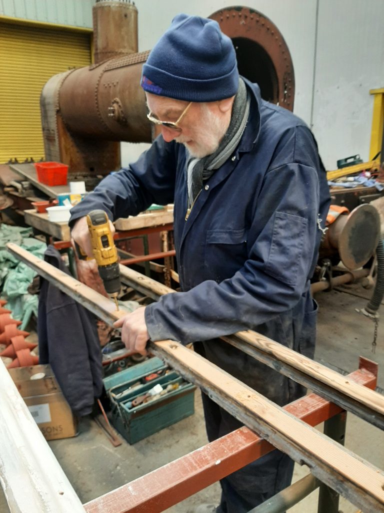 Phil Bell drilling new screw holes in the wooden roof canvas retaining strips