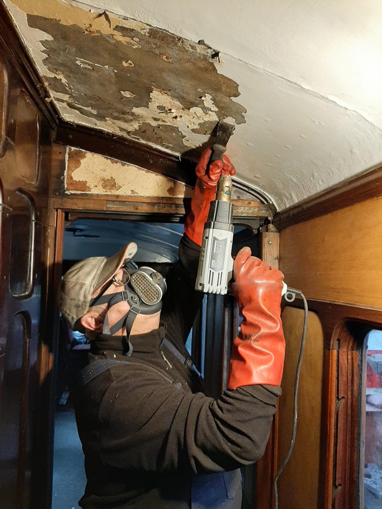 John Davis removing paint from GER 5's corridor ceiling