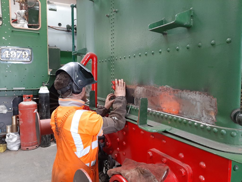 Matt Crabtree using a magnet to position a new piece of steel on the back of Wootton Hall's tender tank