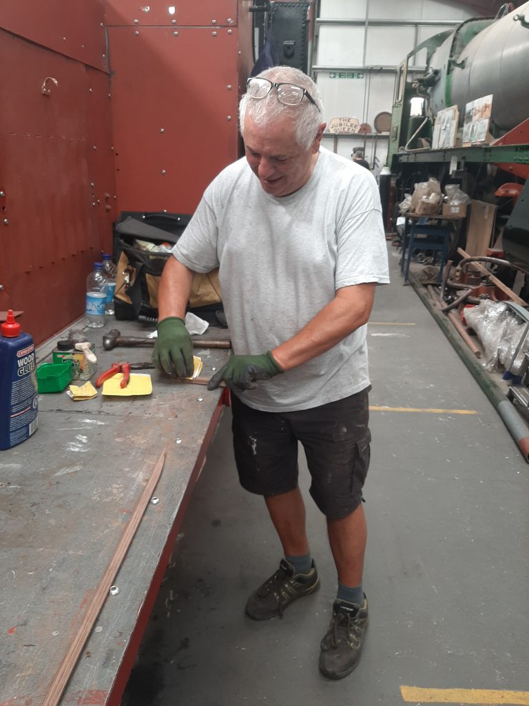 John Davis cleaning a piece of wooden beading from GER No.5