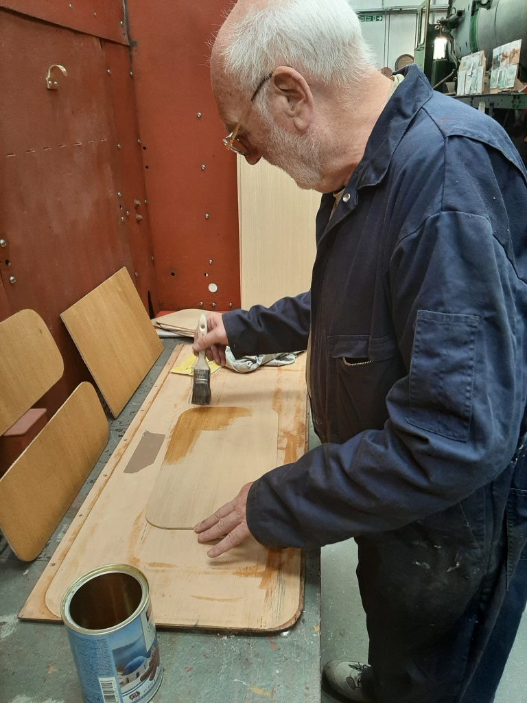 Phil Bell applying a first coat of varnish to a new veneer panel