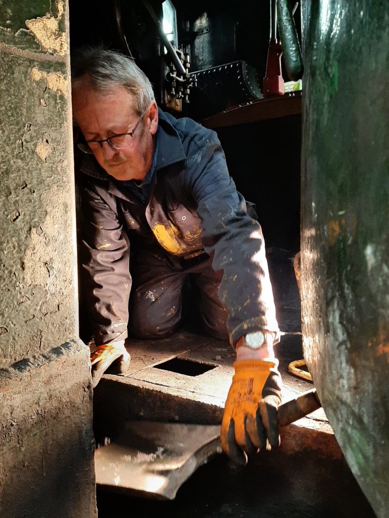 Paul Balshaw shovel out coal dust from beneath 5643's cab floor