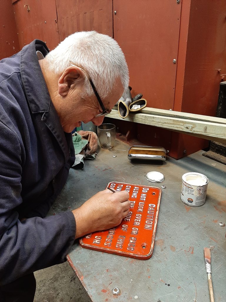 John Davis re-painting the cab warning plate from 5643