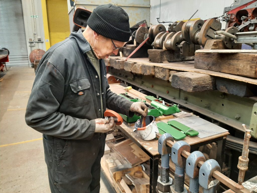 John Dixon applying grey undercoat paint to 5643's spring hanger bolts
