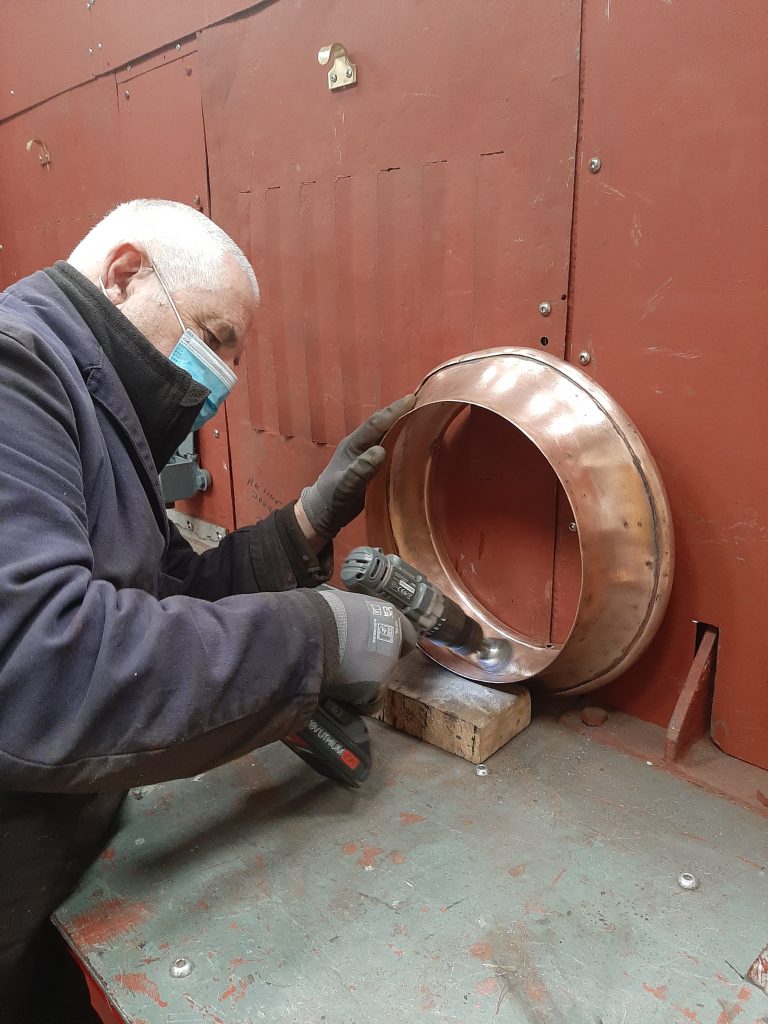 John Davies cleans the copper cap to Fluff's chimney