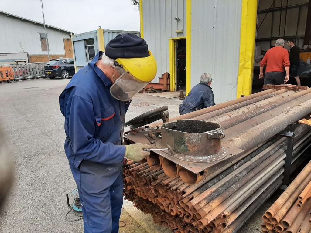 Ed chips away at old rust and paint on one of one of 5643's tank filler appertures